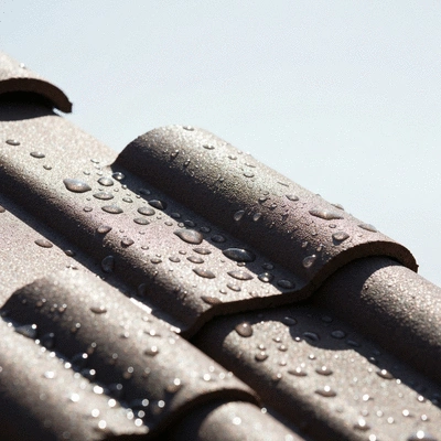 Gros plan sur une tuile de toit cassée avec des gouttes d'eau